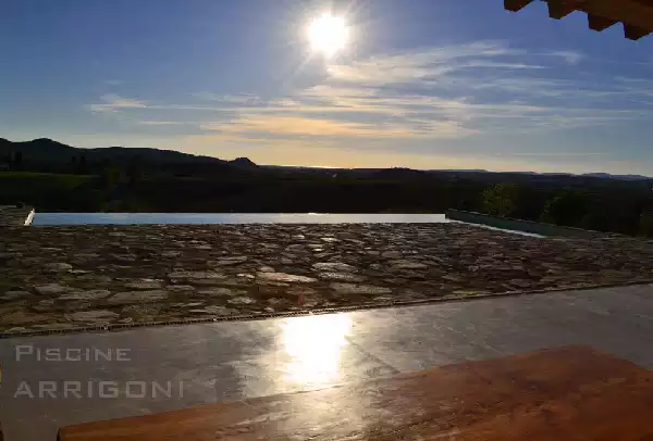 Piscina con sfioro a cascata, vista sul tramonto